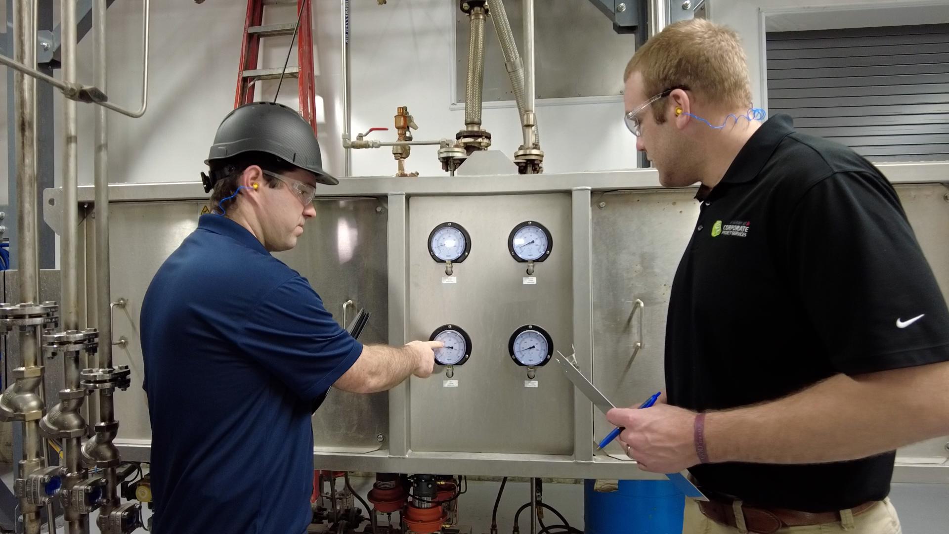 Two techs checking the dials on a machine